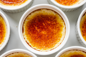 "A beautifully caramelized Crab Brulee served in a white ramekin, topped with a golden sugar crust."