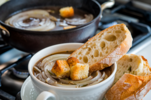 "A steaming bowl of French onion soup with melted cheese and bread"